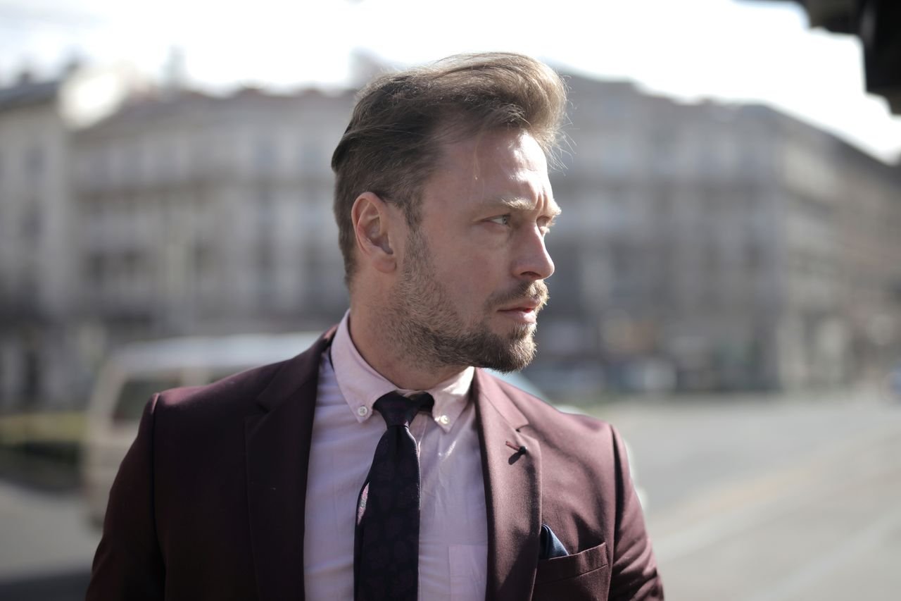 Professional man in suit on city street, looking pensive under daylight.